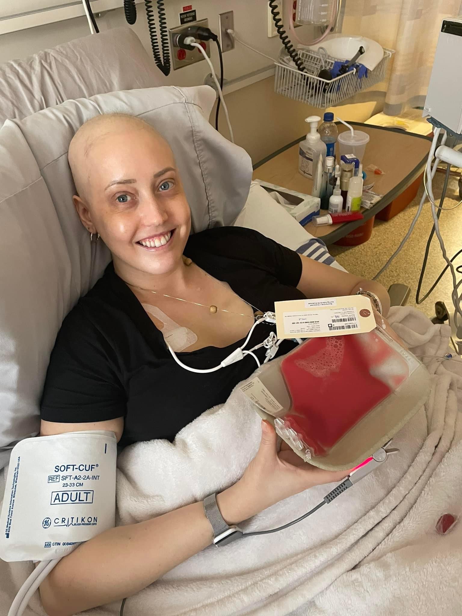 Ashley on a hospital bed holding a blood plasma bag