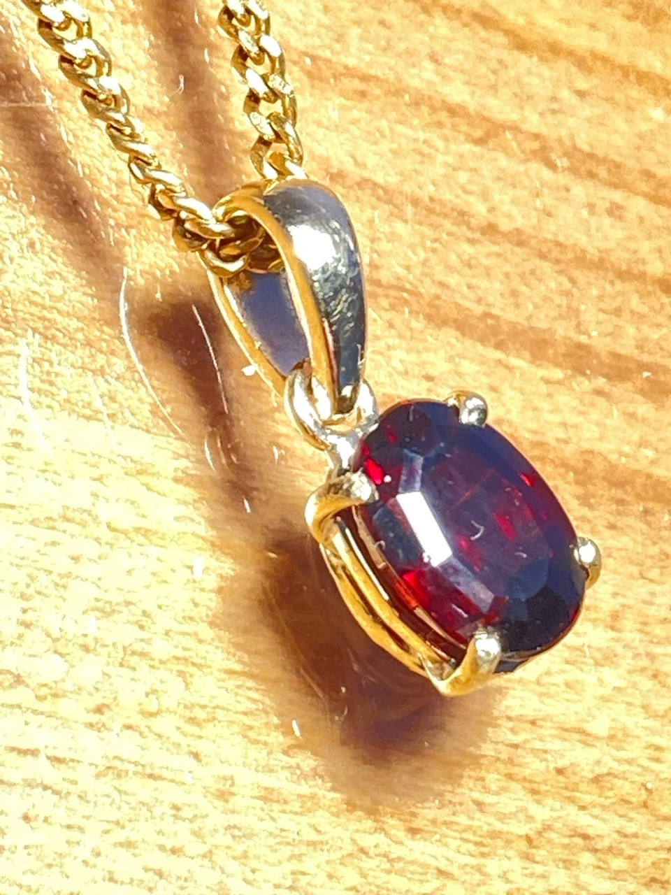 A close-up of a gold pendant with a dark red gem in the middle
