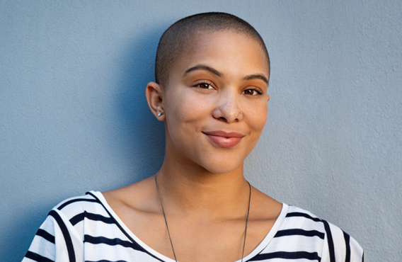 Woman standing against a wall smiling.