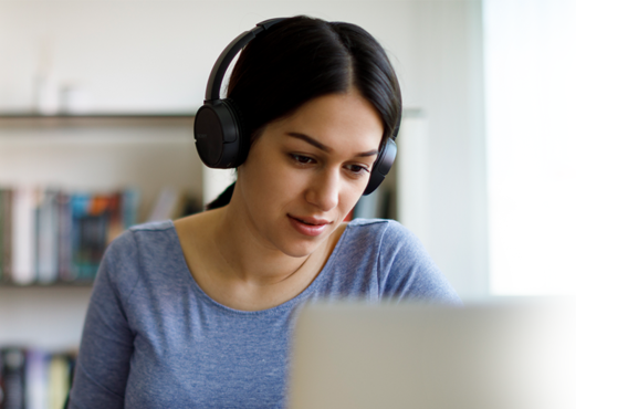 Woman wearing headphones while looking at a computer