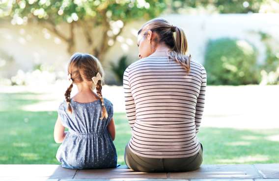 A mother and her child sitting outside looking at a tree