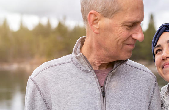 A man and a woman smiling at each other by a lake