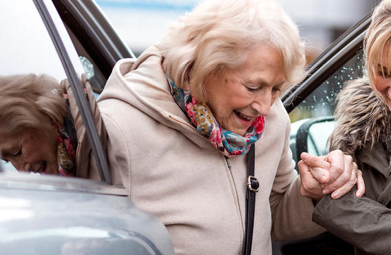 A woman helping an old woman out of a vehicle