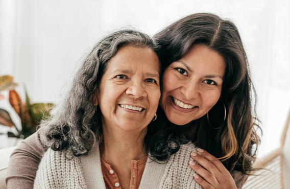 Two women smiling in front of a light white background