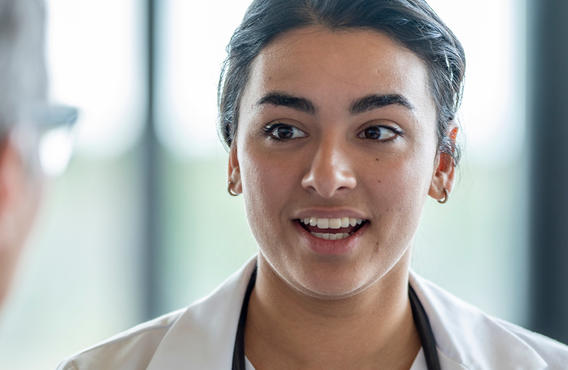 A female doctor talking with a male doctor. The perspective is from behind the male doctor's head.