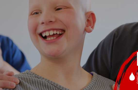 A boy smiling while ringing a bell with a nurse.