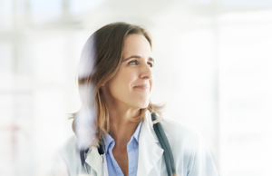 A female doctor smiling while looking off into the distance.