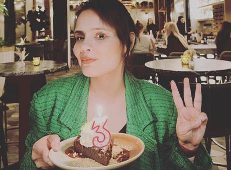 Harjeet Kaur smiling and holding a piece of cake with the number 3.