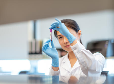 Female laboratory worker inspecting a vial.