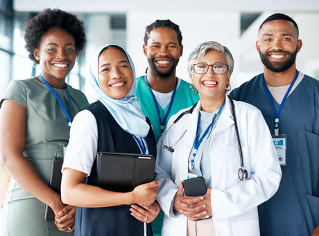 A group of health care professionals standing together in a hallway and smiling