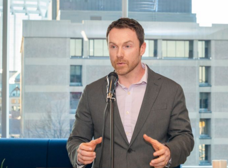 Paul standing at a podium speaking into a microphone