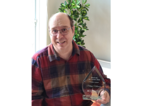 A man in a plaid shirt holds an award.