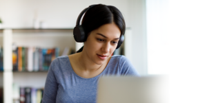 Woman wearing headphones while looking at a computer