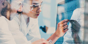Two people analyzing charts on a computer screen