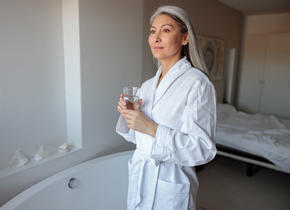 Woman wearing a bathrobe and drinking water