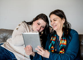 Two smiling women looking at a tablet.