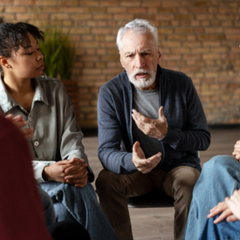 iverse group of individuals engaged in listening to a senior man sharing insights during a supportive group therapy session