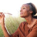 A woman holding a feather outside touching long grass