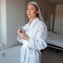 Woman wearing a bathrobe and drinking water