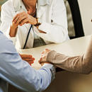 Two people holding hands while talking to a Doctor.