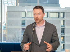 Paul standing at a podium speaking into a microphone