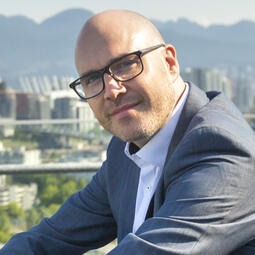 Dr Kuchenbauer sits outside with the city of Vancouver behind him