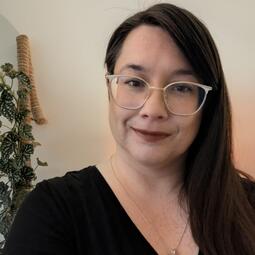 A woman with glasses looks at the camera