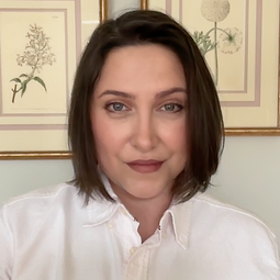 A woman in a white shirt looks at the camera