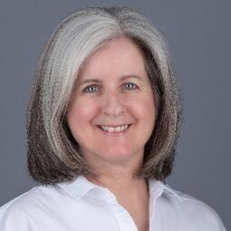a woman in a white shirt looks at the camera