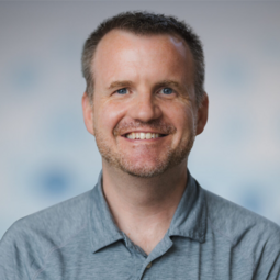 A White man wearing a gray golf shirt looks at the camera.
