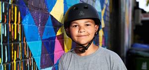 A boy named Justin with headphones standing next to a colorful wall.